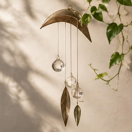 Leaf-inspired hanging decoration with three clear glass spheres and two metal leaves, without text overlay