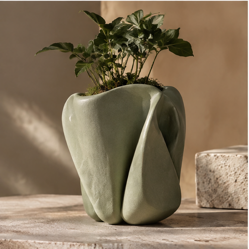 Sage-green sculptural ceramic planter with folded contours and foliage, without text overlay
